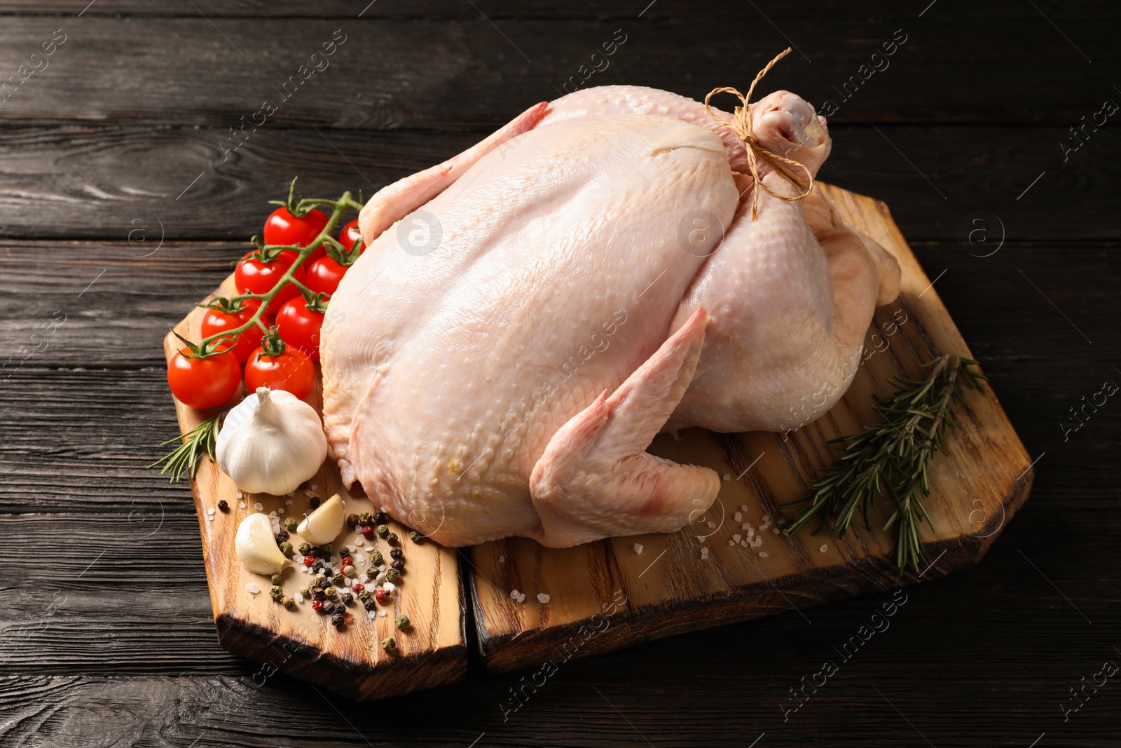 Photo of Board with raw turkey and ingredients on wooden background