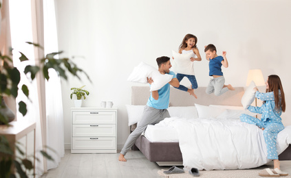 Happy family having pillow fight in bedroom