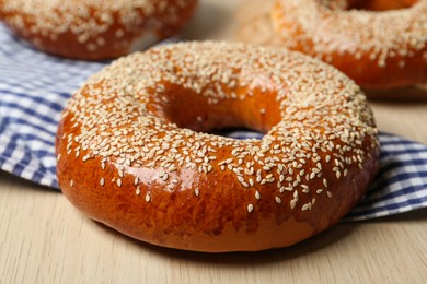 Photo of Delicious fresh bagel with sesame seeds on light wooden table, closeup