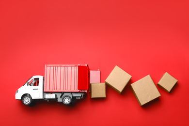 Photo of Top view of toy truck with boxes on red background. Logistics and wholesale concept