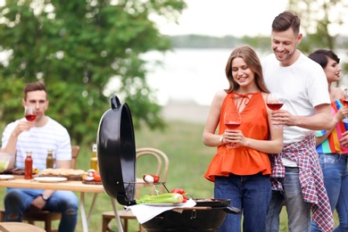 Photo of Young people having barbecue with modern grill outdoors