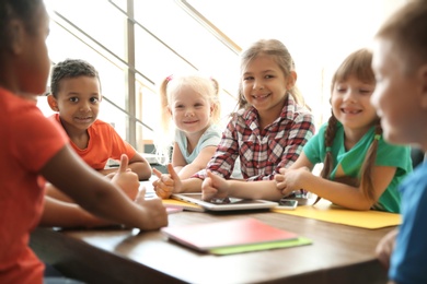 Photo of Little children sitting together at table indoors. Unity concept