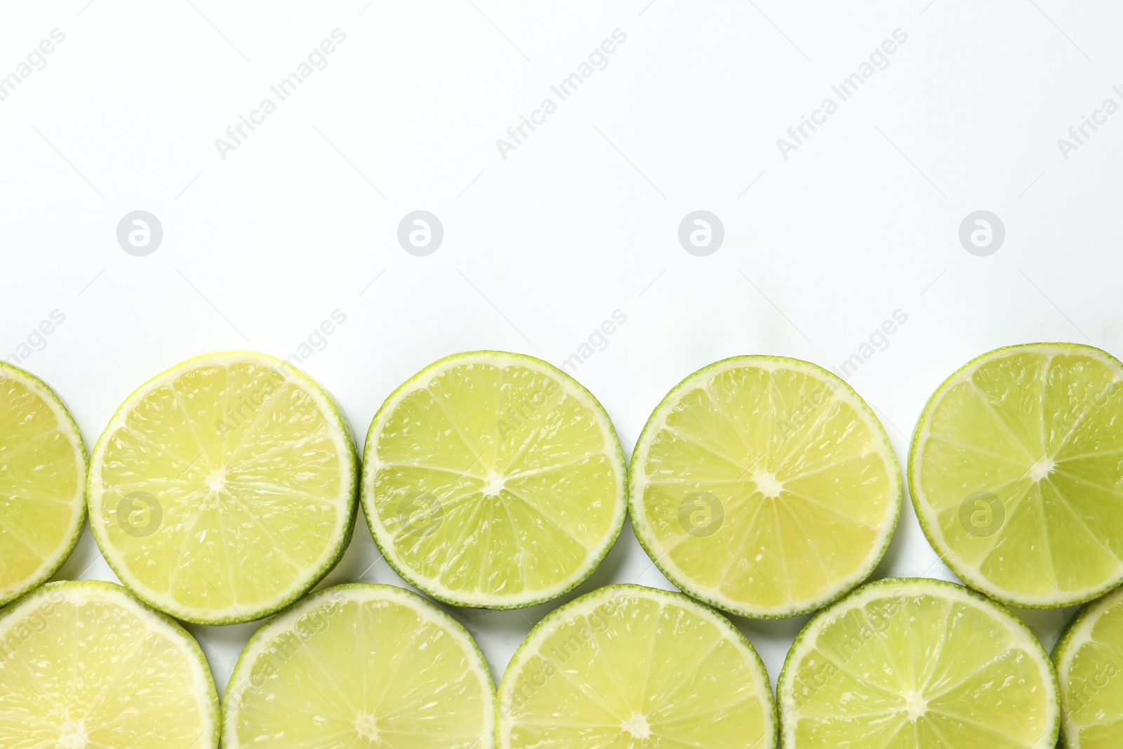 Photo of Fresh juicy lime slices on white background, flat lay. Space for text