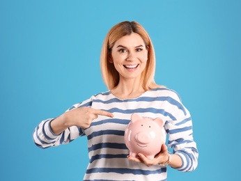 Photo of Woman with piggy bank on color background