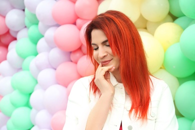 Photo of Young woman with bright dyed hair near colorful balloons