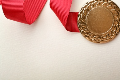 Gold medal on white background, top view with space for text. Symbol of victory