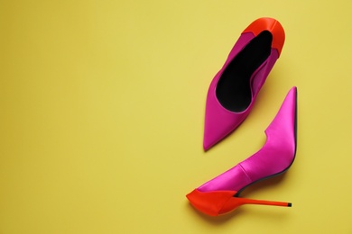 Pair of beautiful shoes on yellow background, top view. Space for text