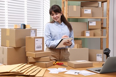 Photo of Parcel packing. Post office worker writing notes indoors