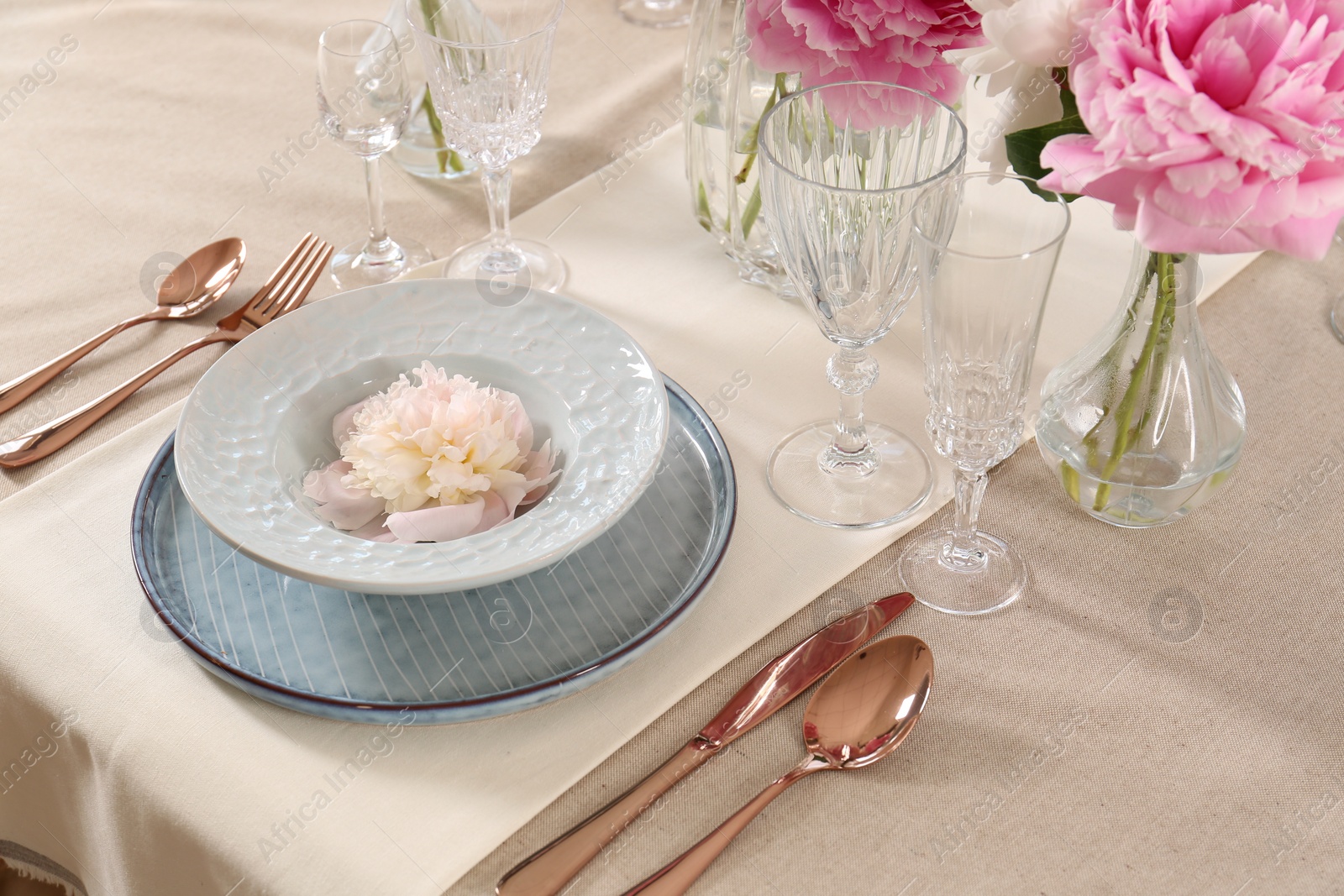 Photo of Stylish table setting with beautiful peonies and golden cutlery