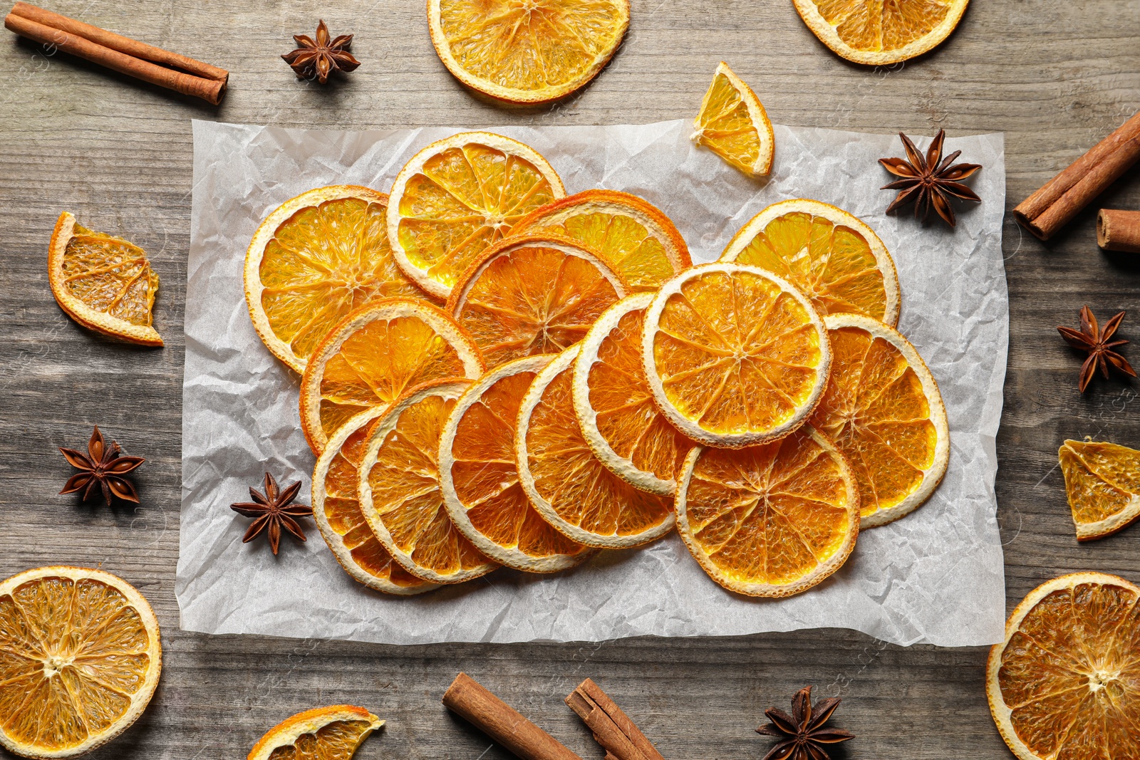 Photo of Many dry orange slices and spices on wooden table, flat lay