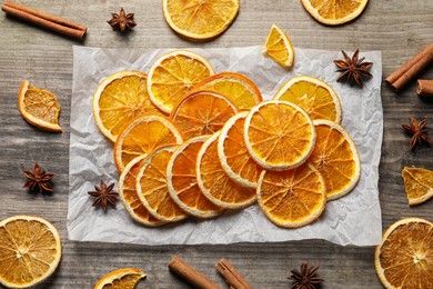 Photo of Many dry orange slices and spices on wooden table, flat lay