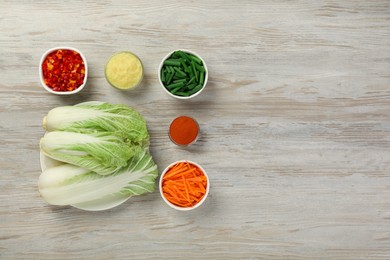 Fresh Chinese cabbages and other kimchi ingredients on wooden table, flat lay. Space for text