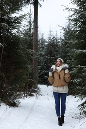 Young woman in conifer forest on snowy day. Winter vacation