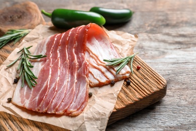 Photo of Board with raw bacon on table, closeup