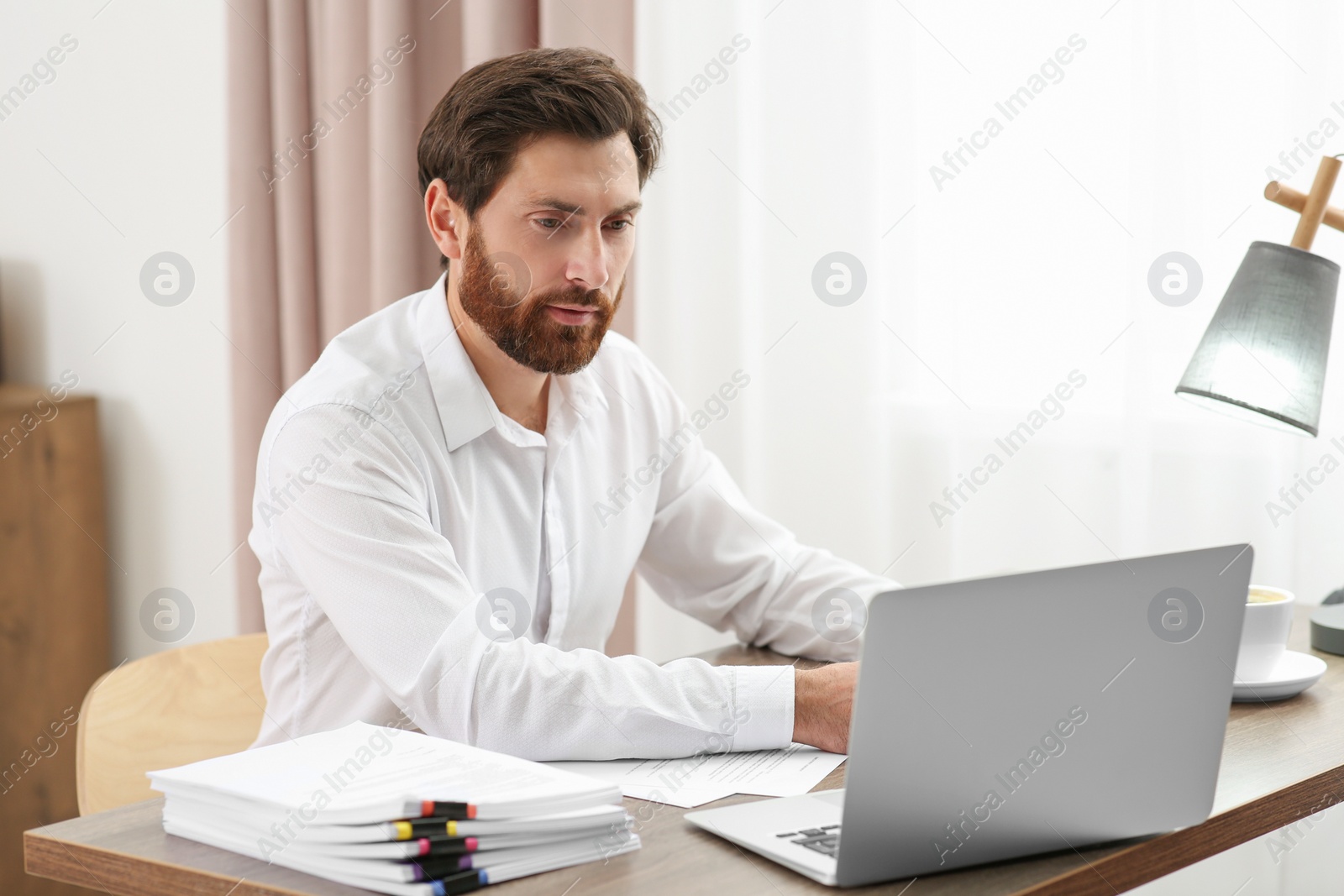 Photo of Businessman working with documents at wooden table in office