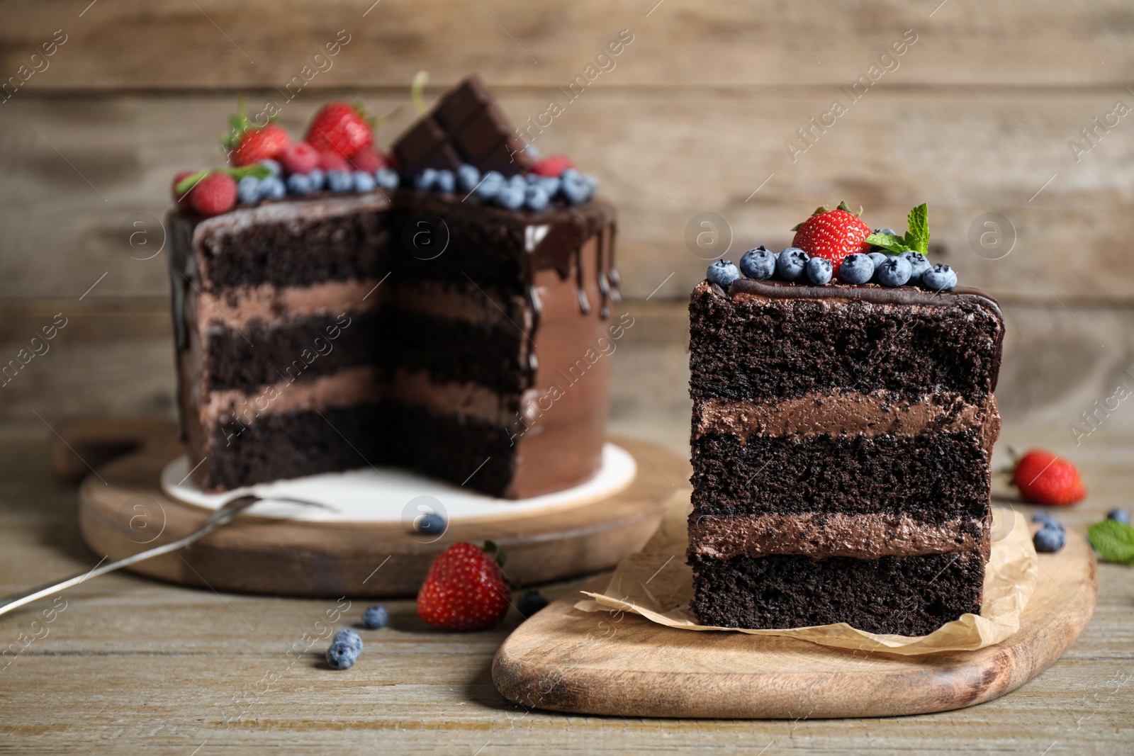 Photo of Delicious chocolate cake decorated with fresh berries on wooden table