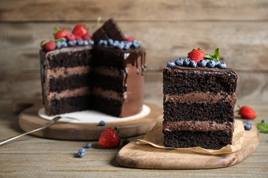 Photo of Delicious chocolate cake decorated with fresh berries on wooden table