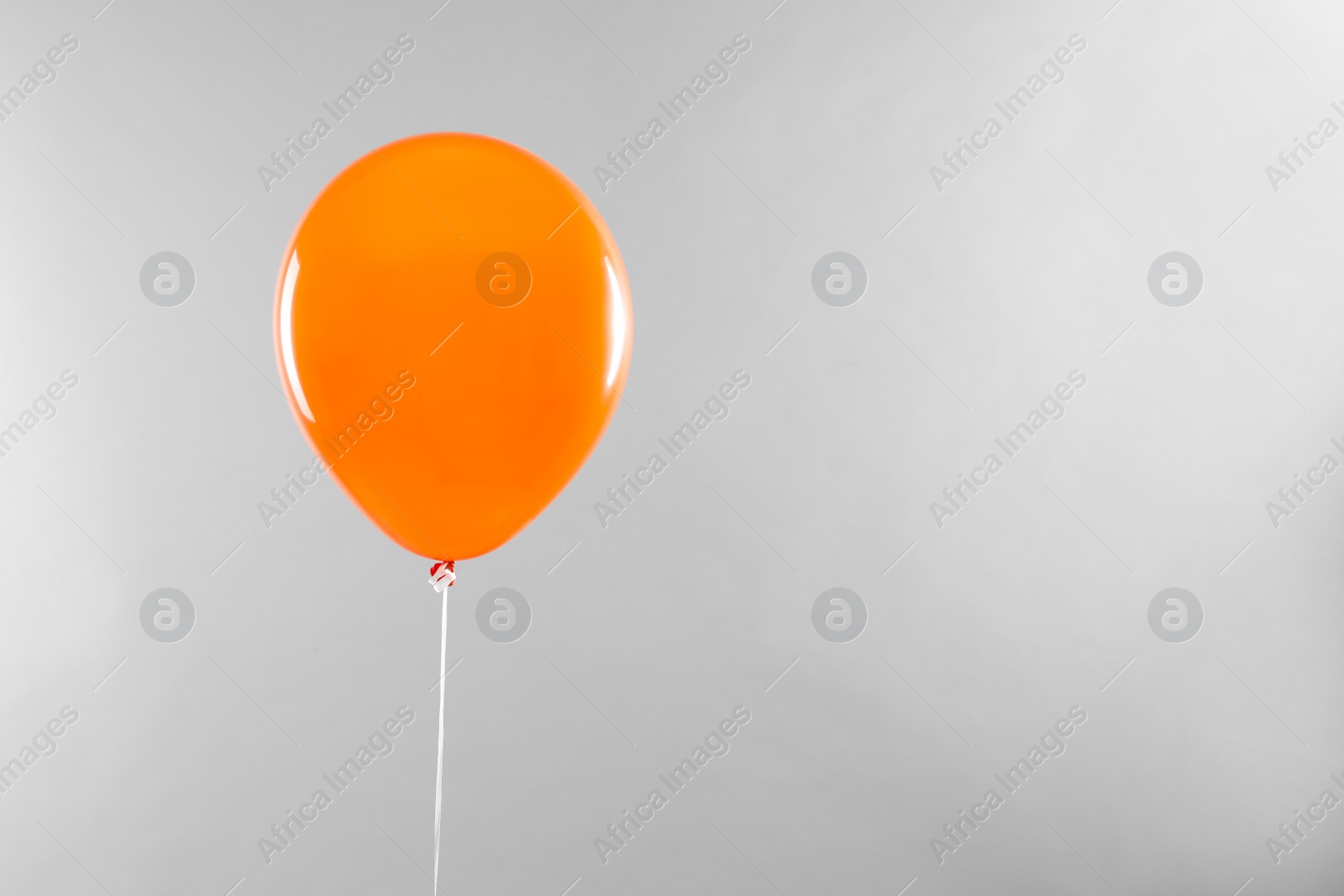 Photo of Orange balloon for Halloween party on light grey background, space for text