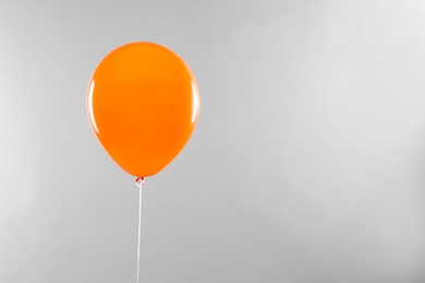Photo of Orange balloon for Halloween party on light grey background, space for text