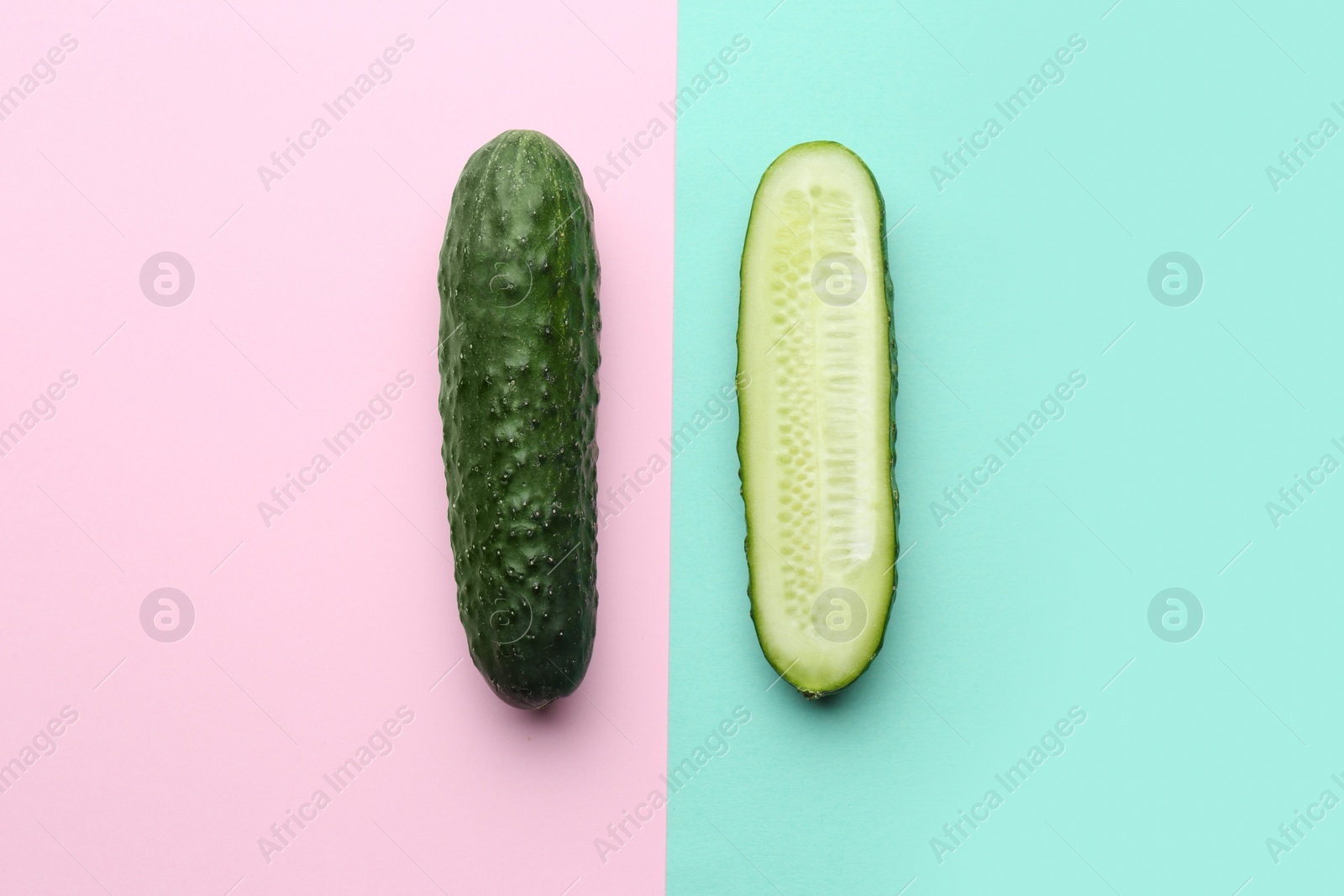 Photo of Whole and cut cucumbers on color background, flat lay