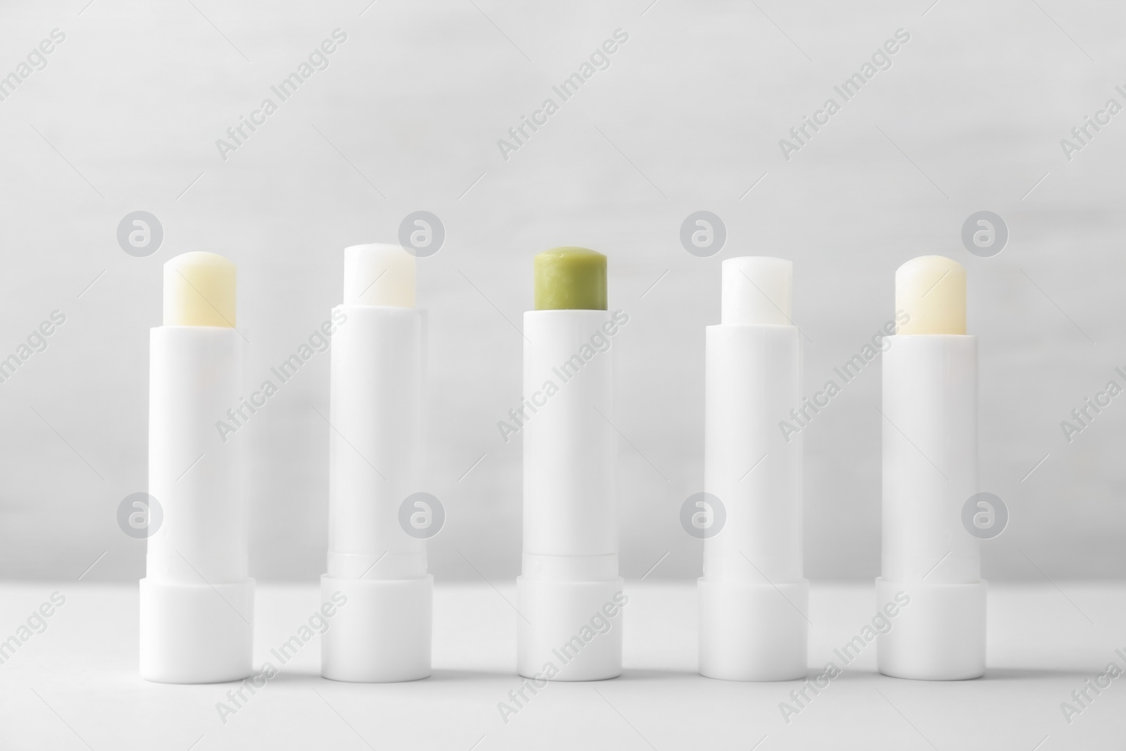 Photo of Hygienic lipsticks on table against light background