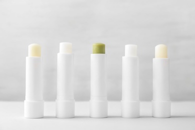 Photo of Hygienic lipsticks on table against light background