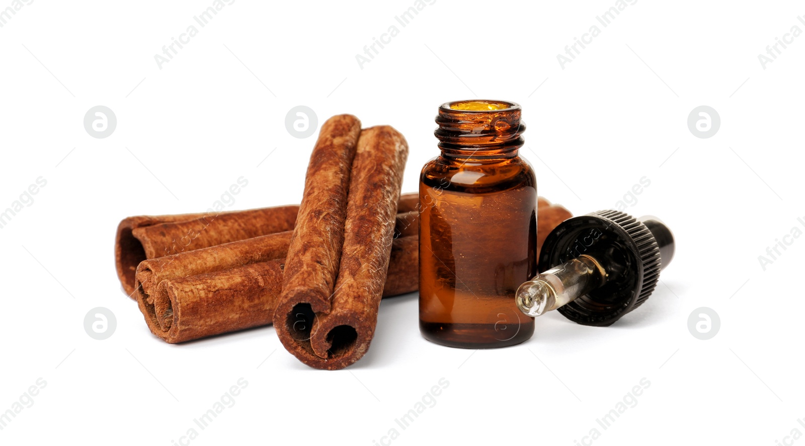 Photo of Bottle of cinnamon oil, dropper and sticks on white background