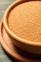 Photo of Brown sugar in bowl on light blue wooden table, closeup