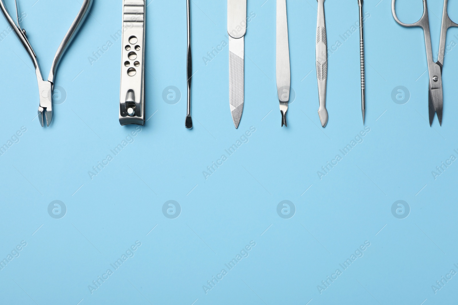 Photo of Set of manicure tools on light blue background, flat lay. Space for text