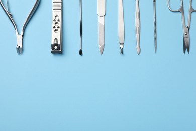 Set of manicure tools on light blue background, flat lay. Space for text
