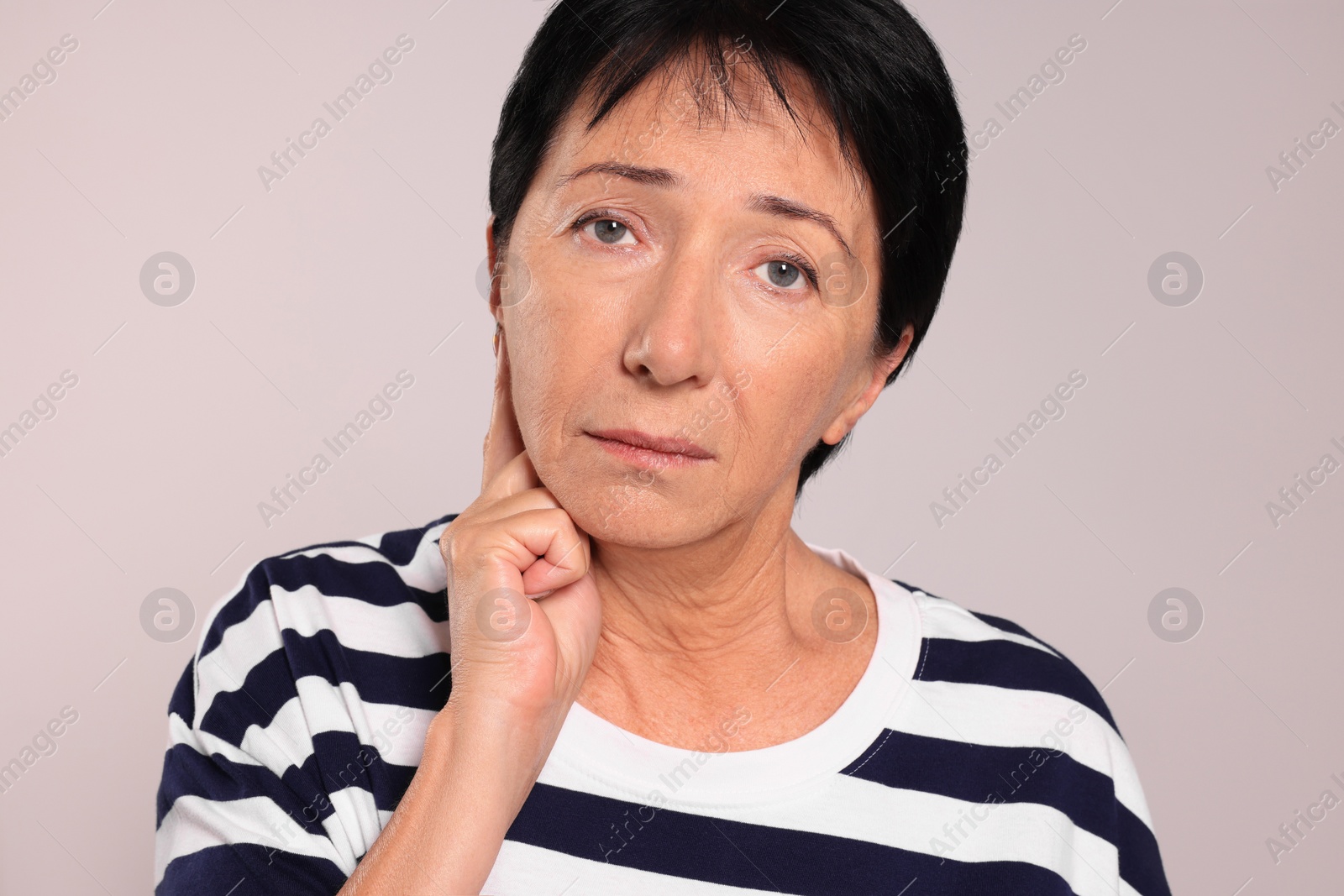 Photo of Senior woman suffering from ear pain on light grey background