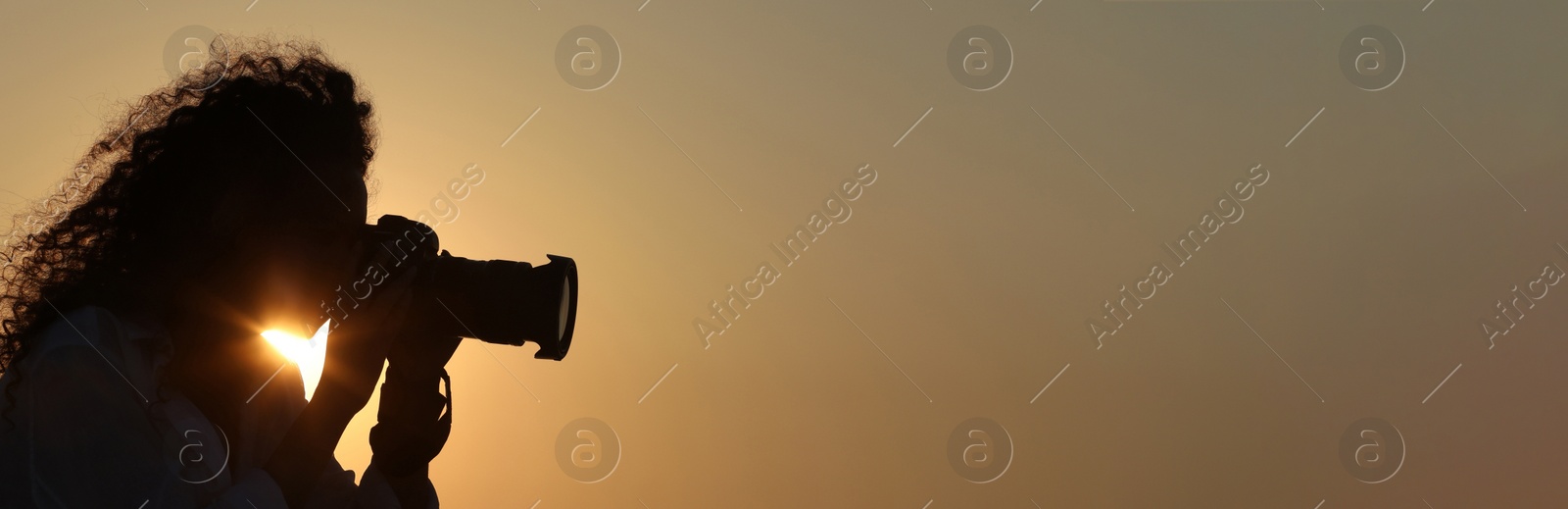 Image of Photographer taking photo with professional camera outdoors at sunset, space for text. Banner design
