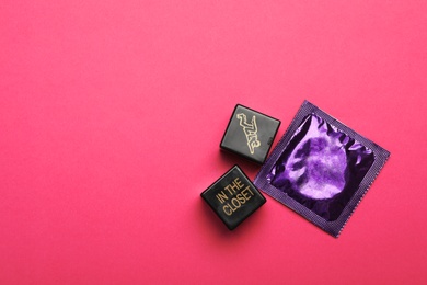 Photo of Sex dice and condom on pink background, top view. Space for text