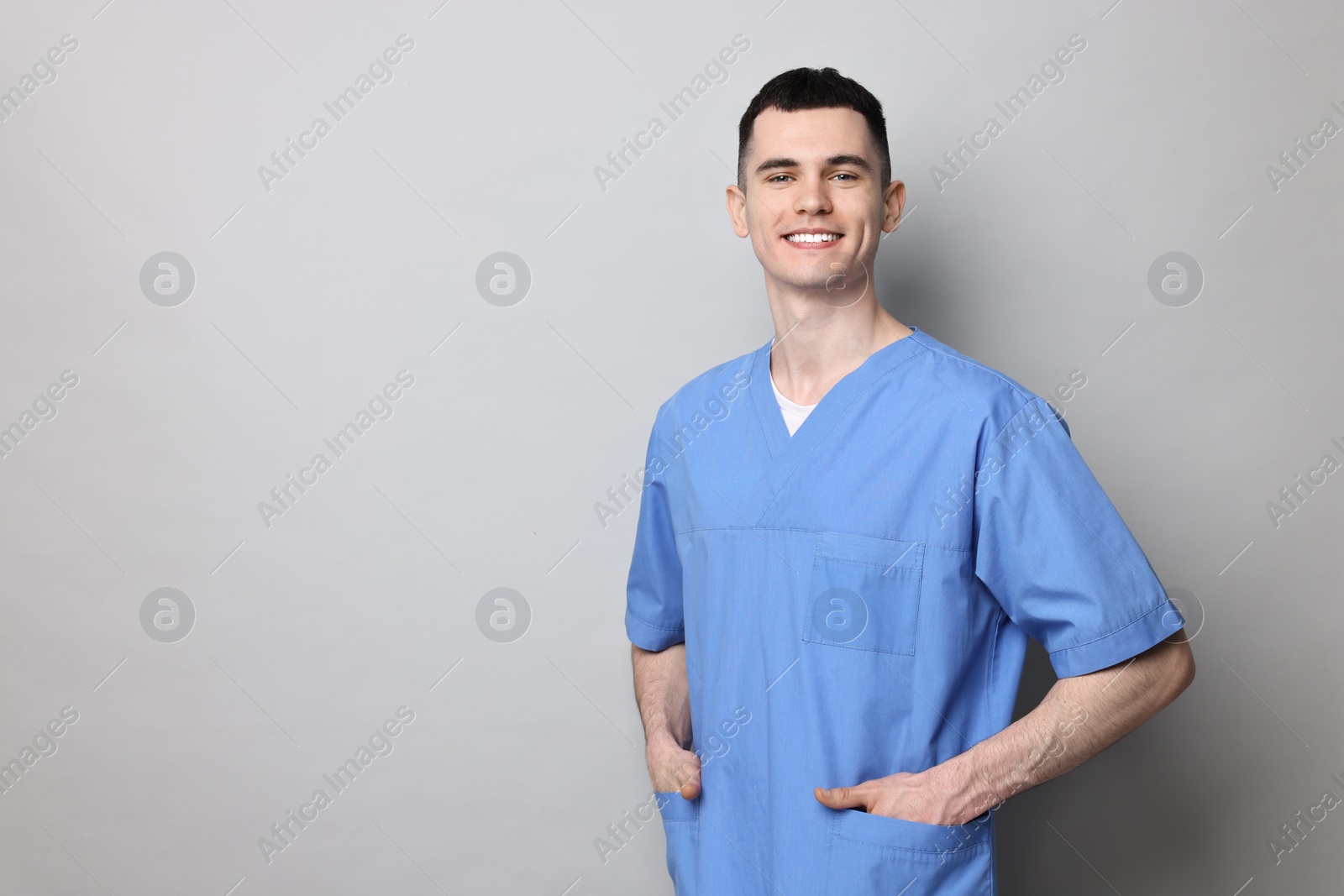 Photo of Portrait of smiling medical assistant on grey background. Space for text