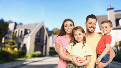 Happy family smiling near their new house on blurred background. Space for text 
