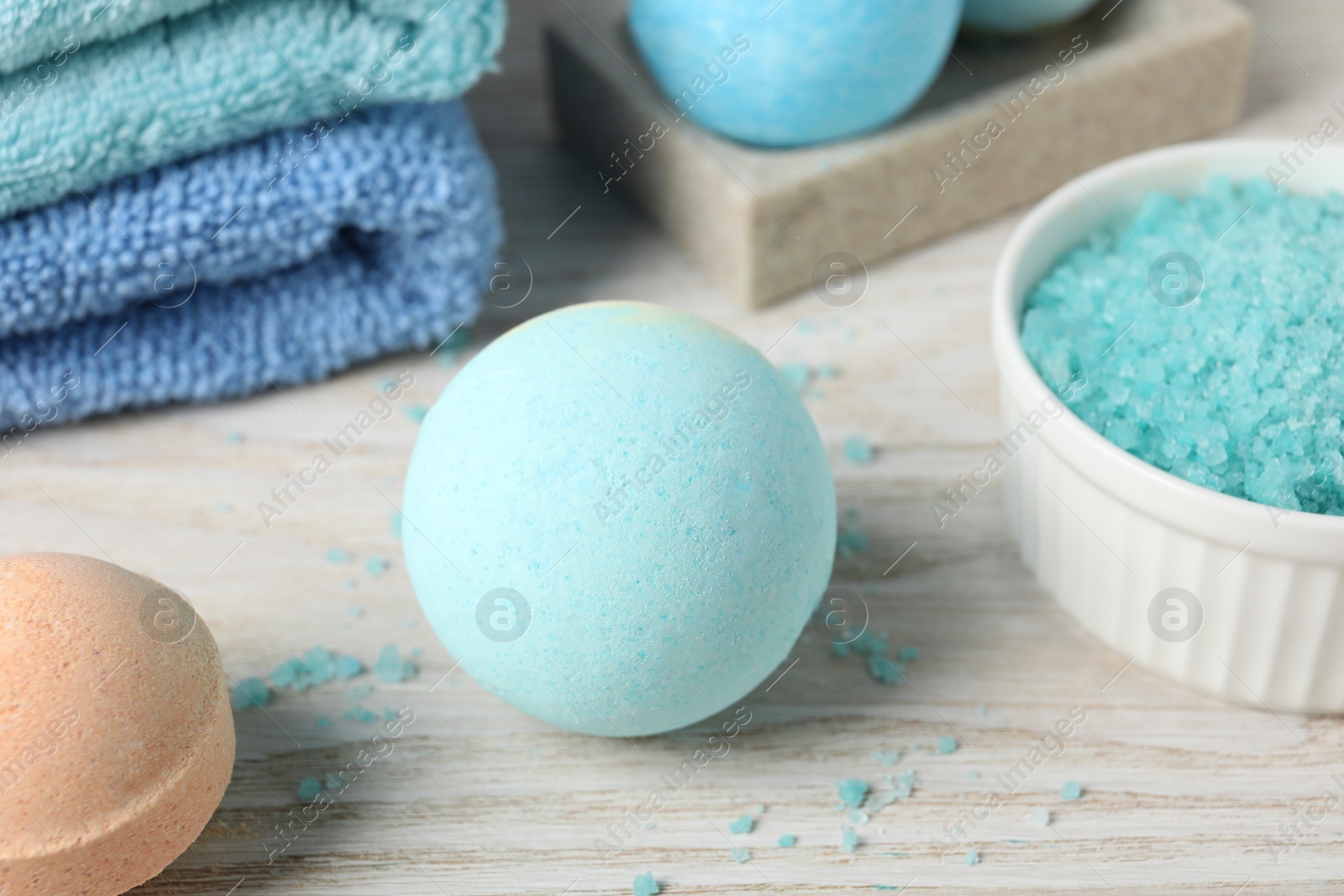 Photo of Beautiful aromatic bath bombs and sea salt on light wooden table, closeup