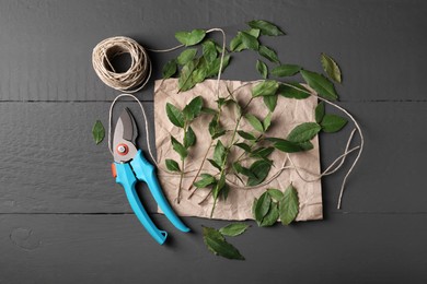 Photo of Fresh green bay leaves, secateurs and twine on grey wooden table, flat lay