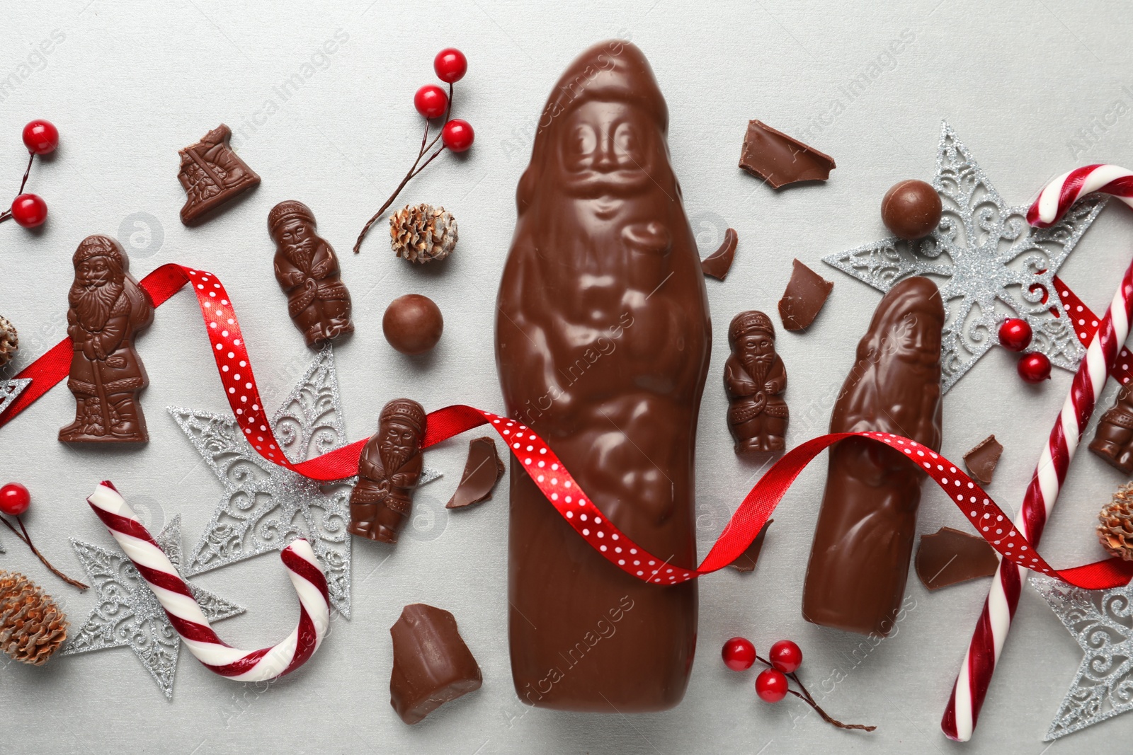Photo of Flat lay composition with chocolate Santa Claus candies and Christmas decorations on light grey table
