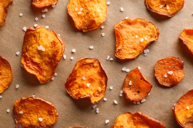 Photo of Sweet potato chips with salt on color background, flat lay