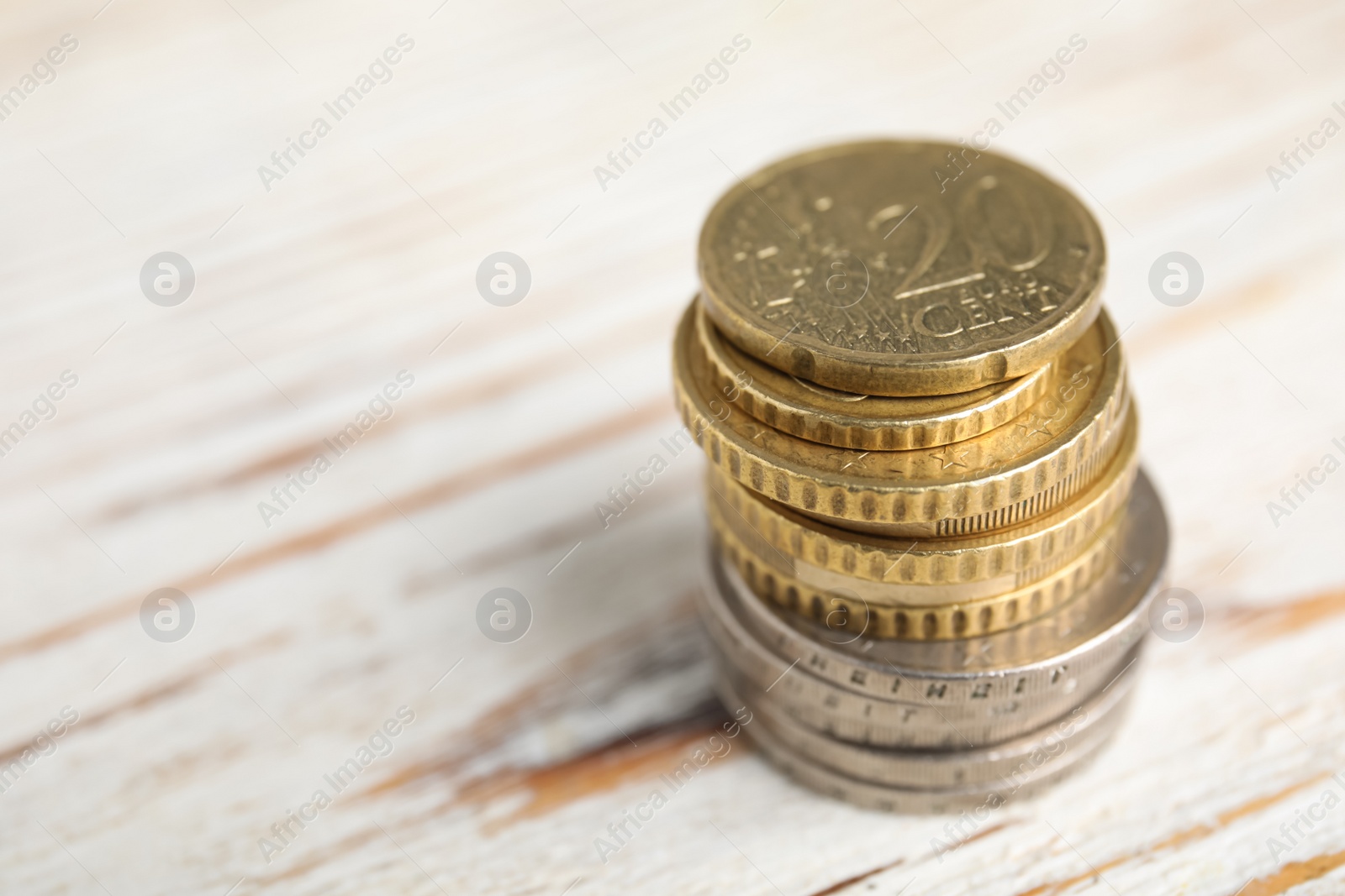 Photo of Many Euro coins stacked on white wooden table, closeup. Space for text