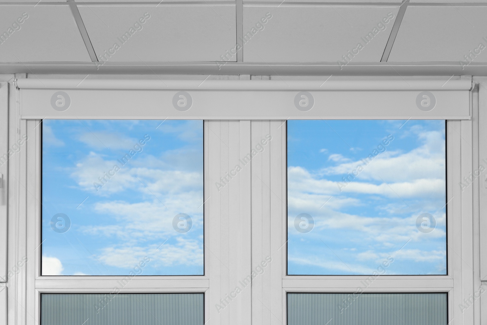 Photo of Plastic windows with white roller blinds indoors