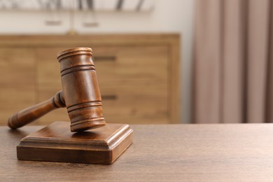 Photo of Wooden gavel and sound block on table indoors, closeup. Space for text