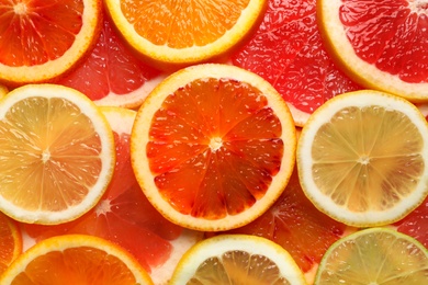 Photo of Slices of fresh citrus fruits as background, top view