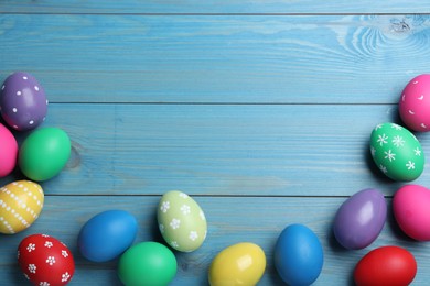 Colorful eggs on blue wooden background, flat lay with space for text. Happy Easter