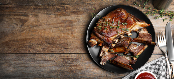 Flat lay composition with delicious roasted ribs on wooden table, space for text. Banner design