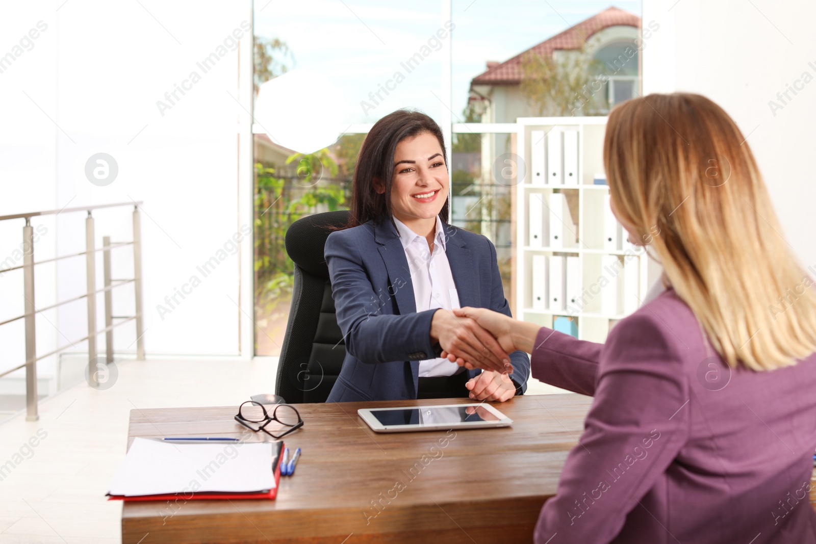 Photo of Human resources manager shaking hands with applicant during job interview in office