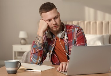 Photo of Online test. Man studying with laptop at home