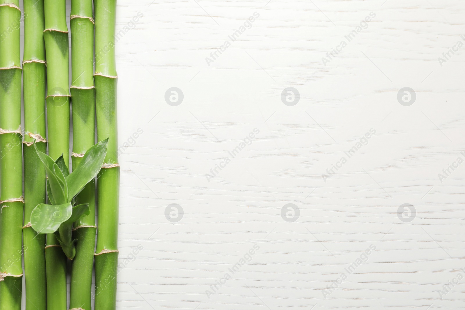 Photo of Green bamboo stems and space for text on wooden background, top view