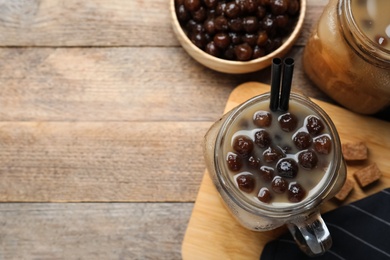 Photo of Tasty milk bubble tea on wooden table, flat lay. Space for text