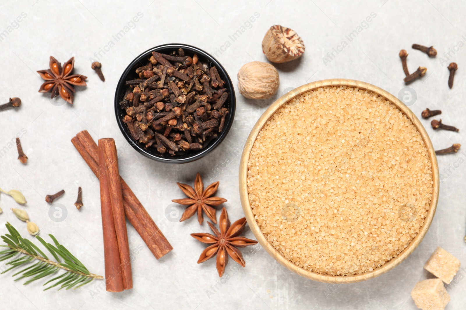 Photo of Different spices in bowls, nuts and fir branch on light gray textured table, flat lay